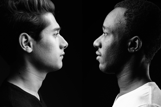 A black and white image of a white and Black man staring at each other.