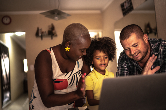 Two adults with a child at home, watching something in front of a computer.