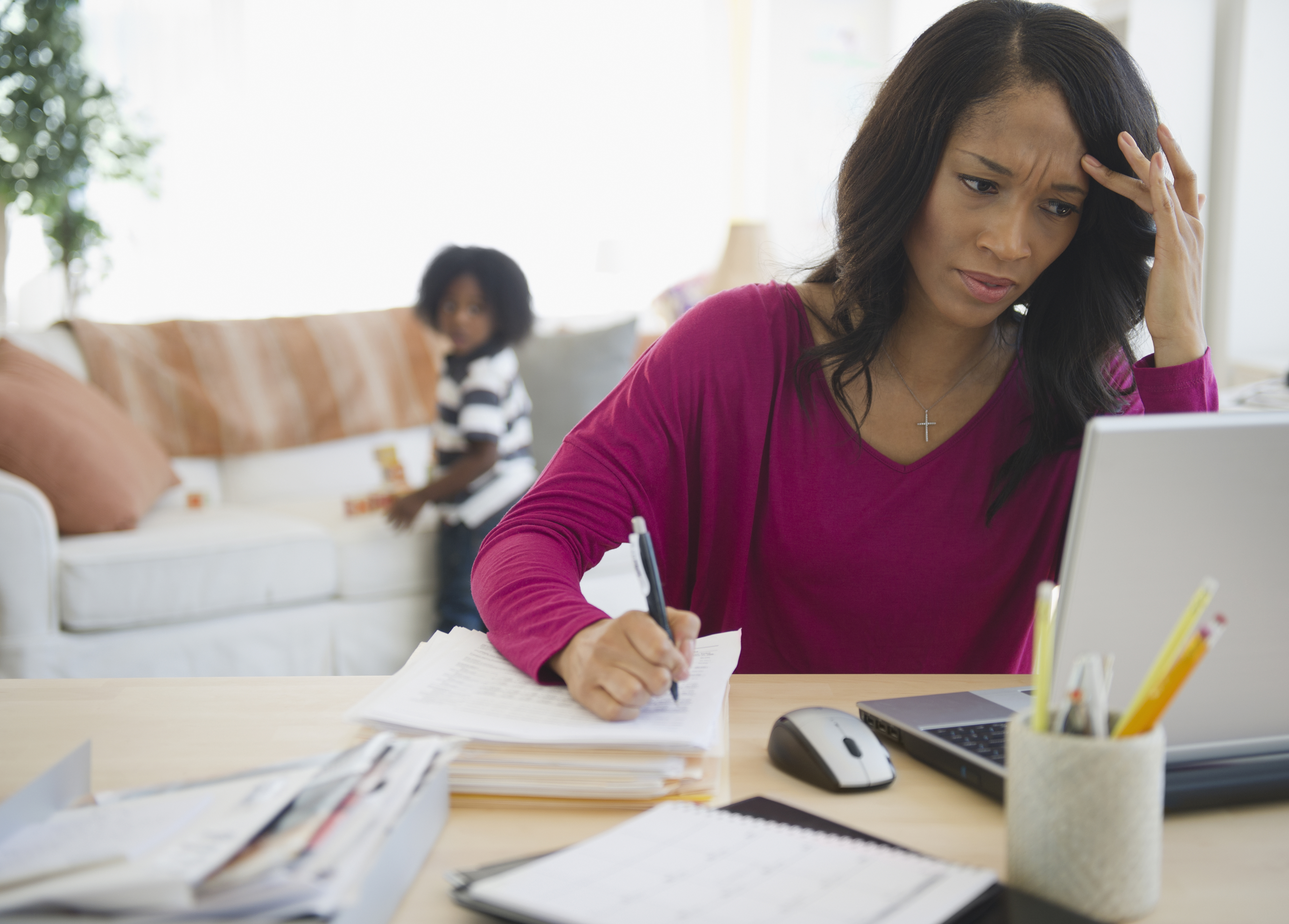 Woman working on laptop while child is looking back at her