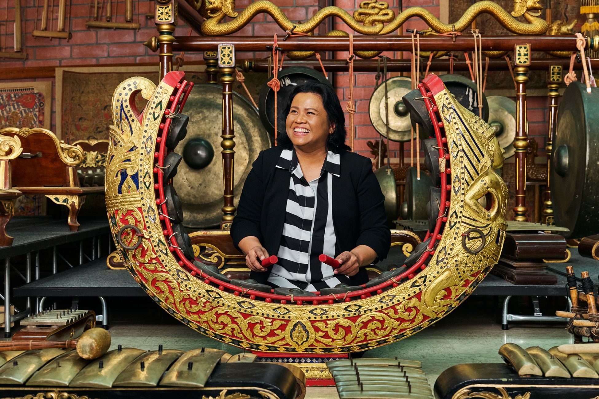 A woman smiles as she sits behind a large musical instrument.