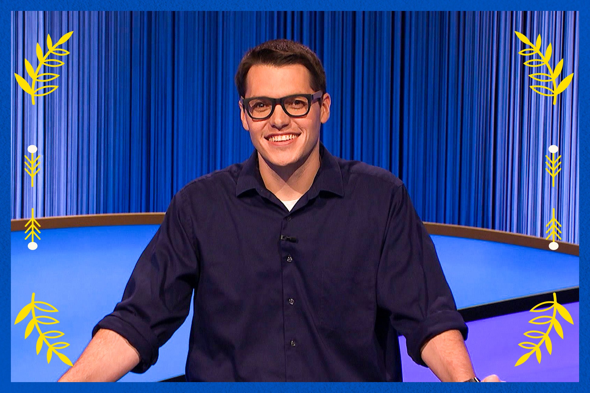  A man wearing glasses stands comfortably and smiles.