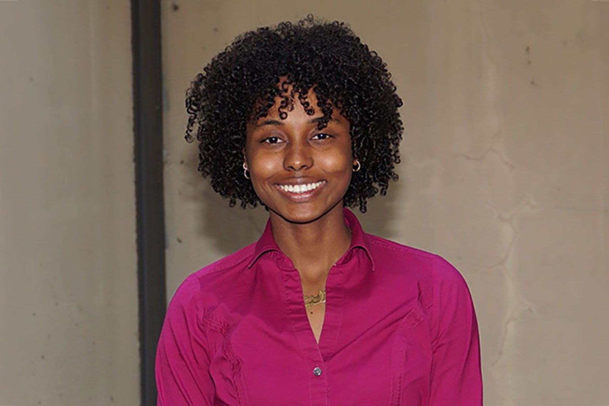 Yong woman smiling wearing a bright pink blouse