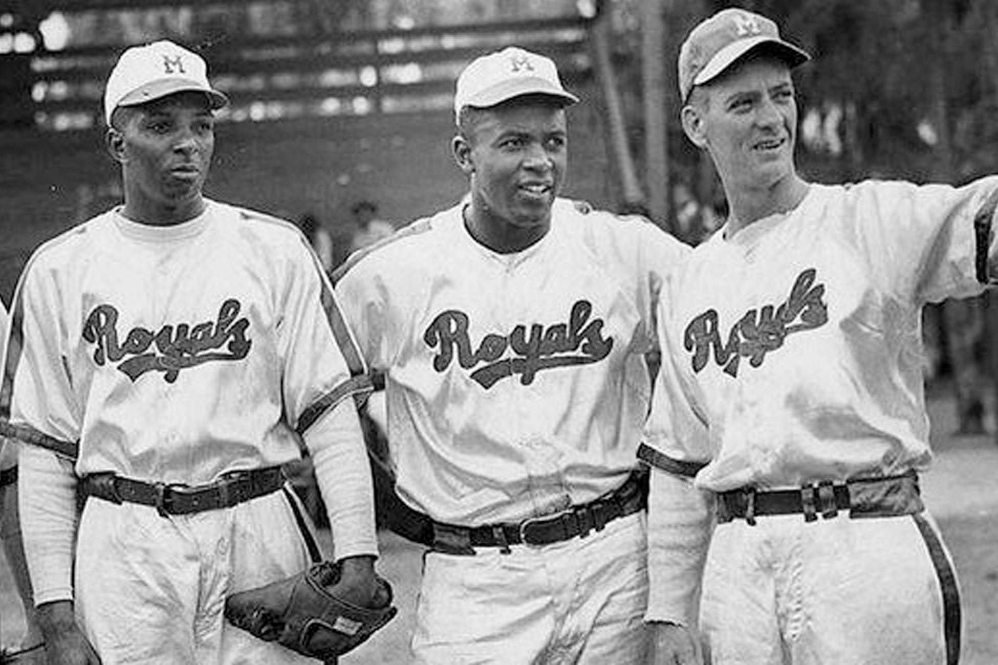 Black-and-white photo of three baseball players in Royals uniforms standing together on the field.