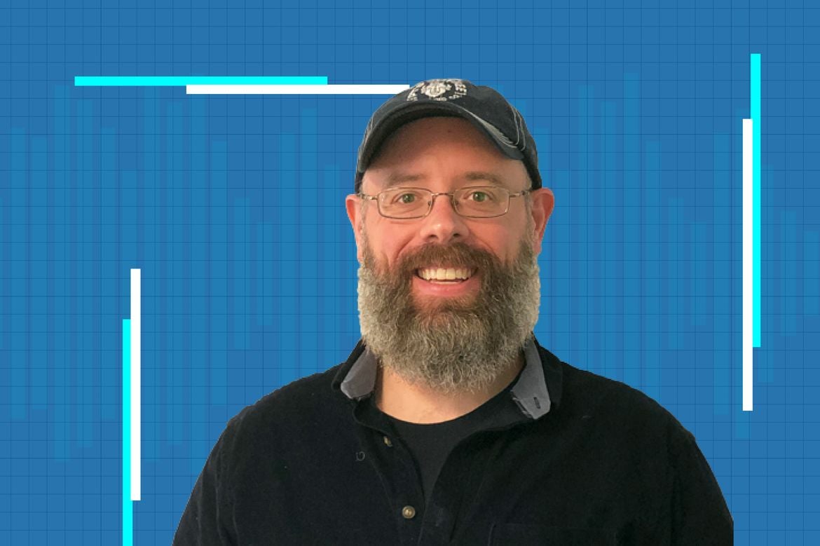 Eric Deeds in a black shirt against a blue grid background