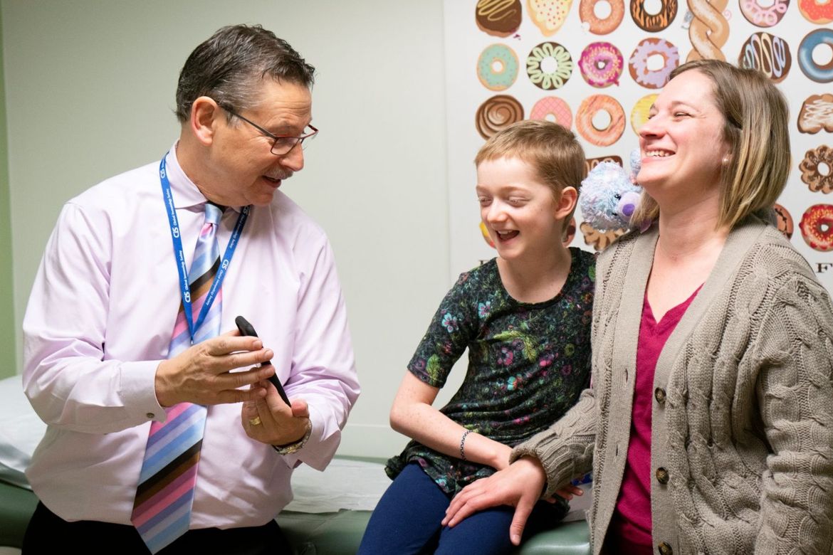 Dr. Donald Kohn holds cell phone up as patient Marley Gaskins and her mother, Tamara Hogue, smile