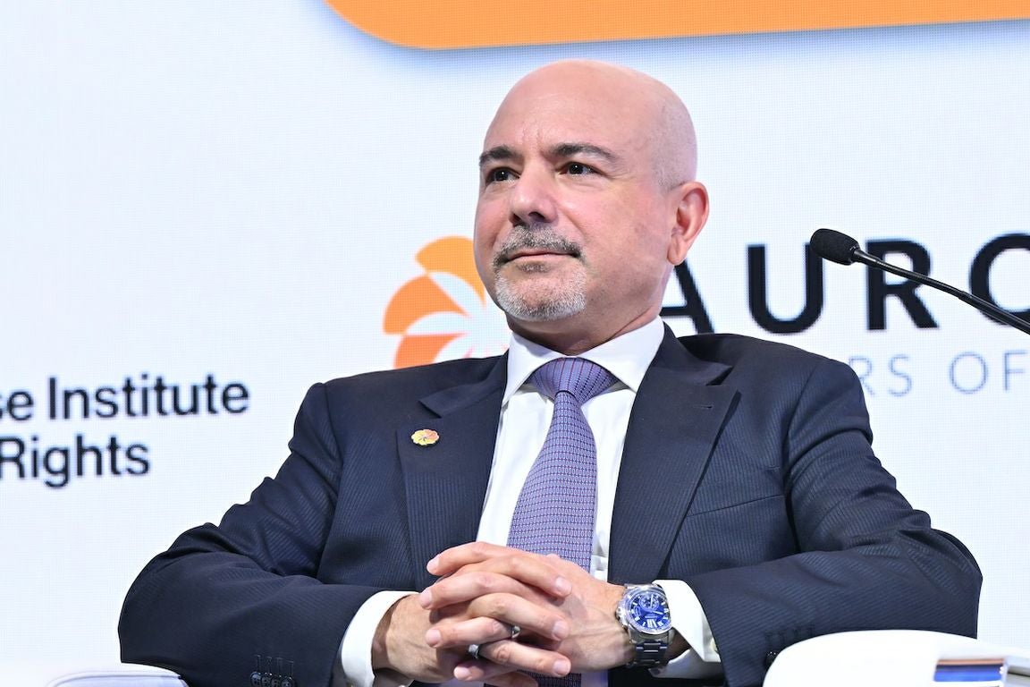 Midrange shot of Eric Esrailian in suit and tie, seated with hands clasped in front