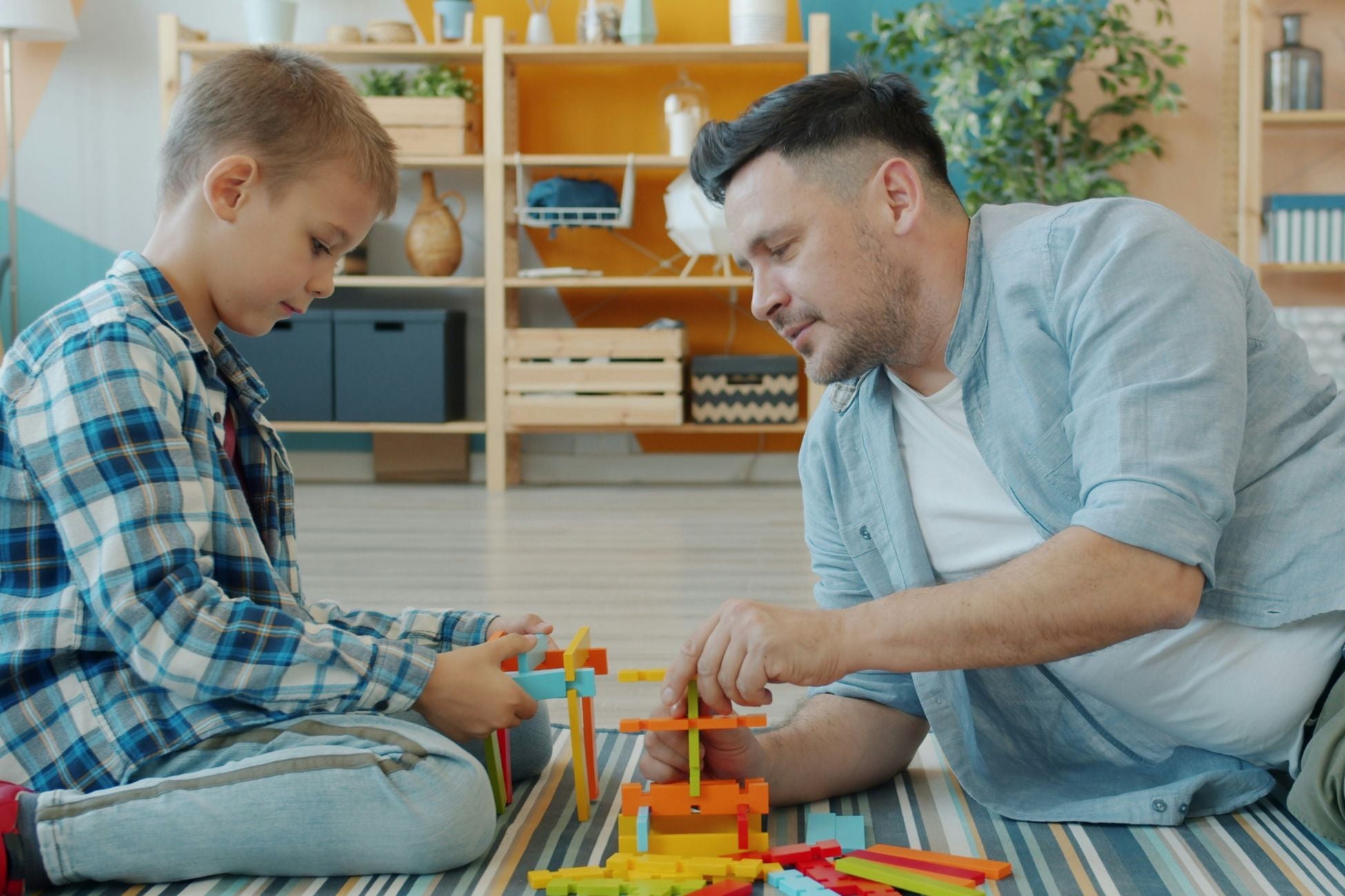 A child and father sit on the floor playing with toys