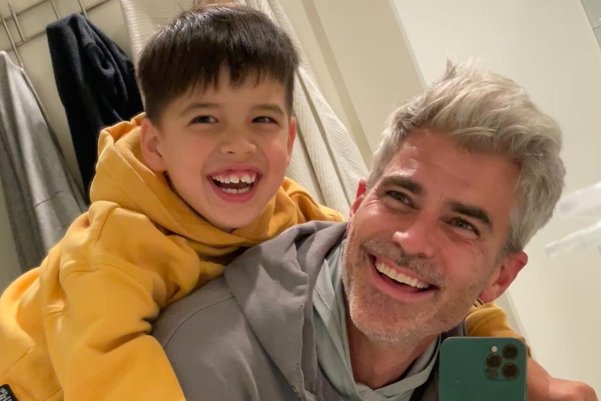 Dad Jeffrey Randall Allen tries to take a cell phone picture with son Lucas on his back