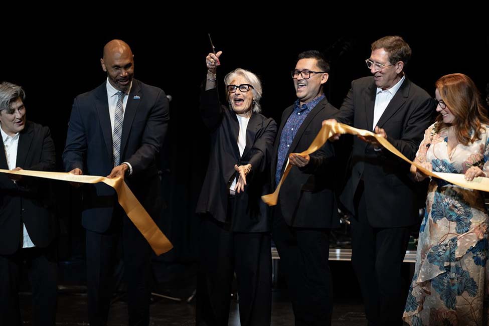 Group of UCLA leaders and donors smiling, laughing, and cutting a gold ribbon to commemorate the opening of the Nimoy theatre