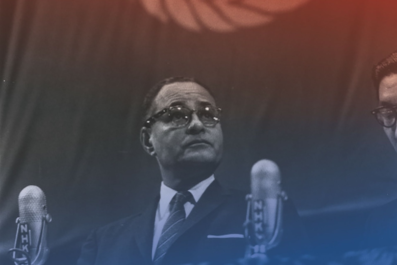 Black-and-white photo of Ralph Bunche speaking in front of two microphones