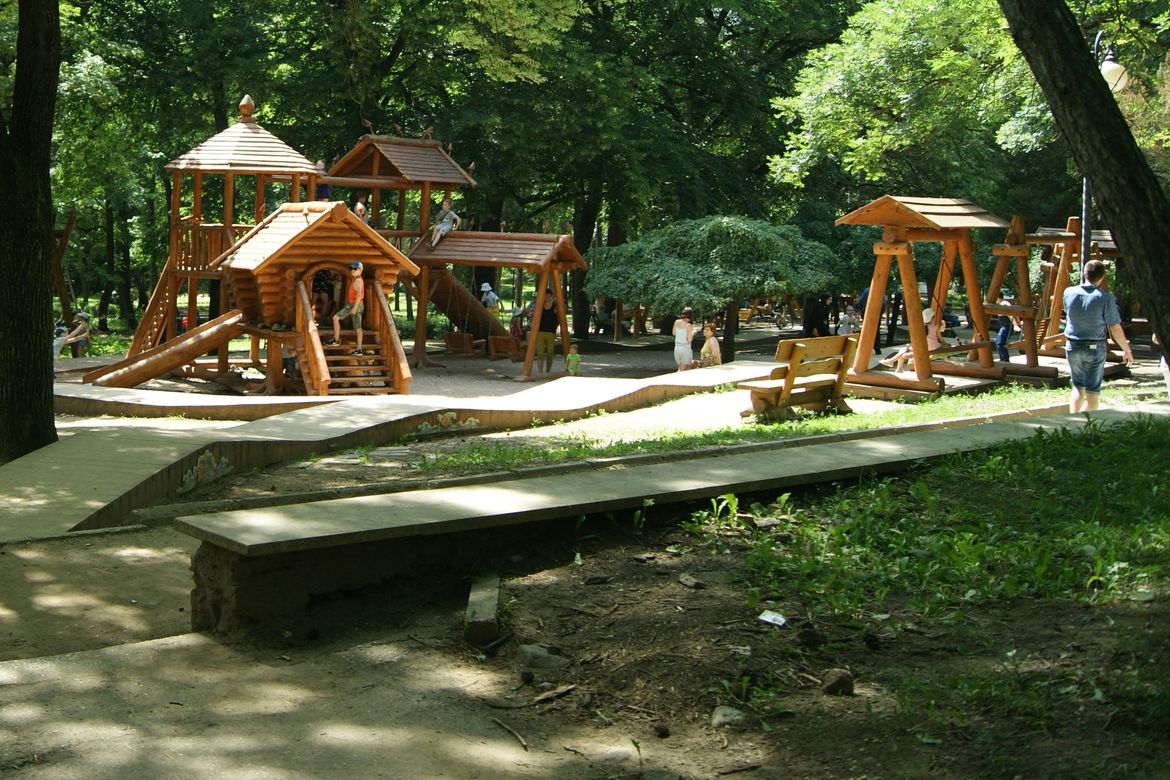 Shaded playground with wooden play equipment for kids