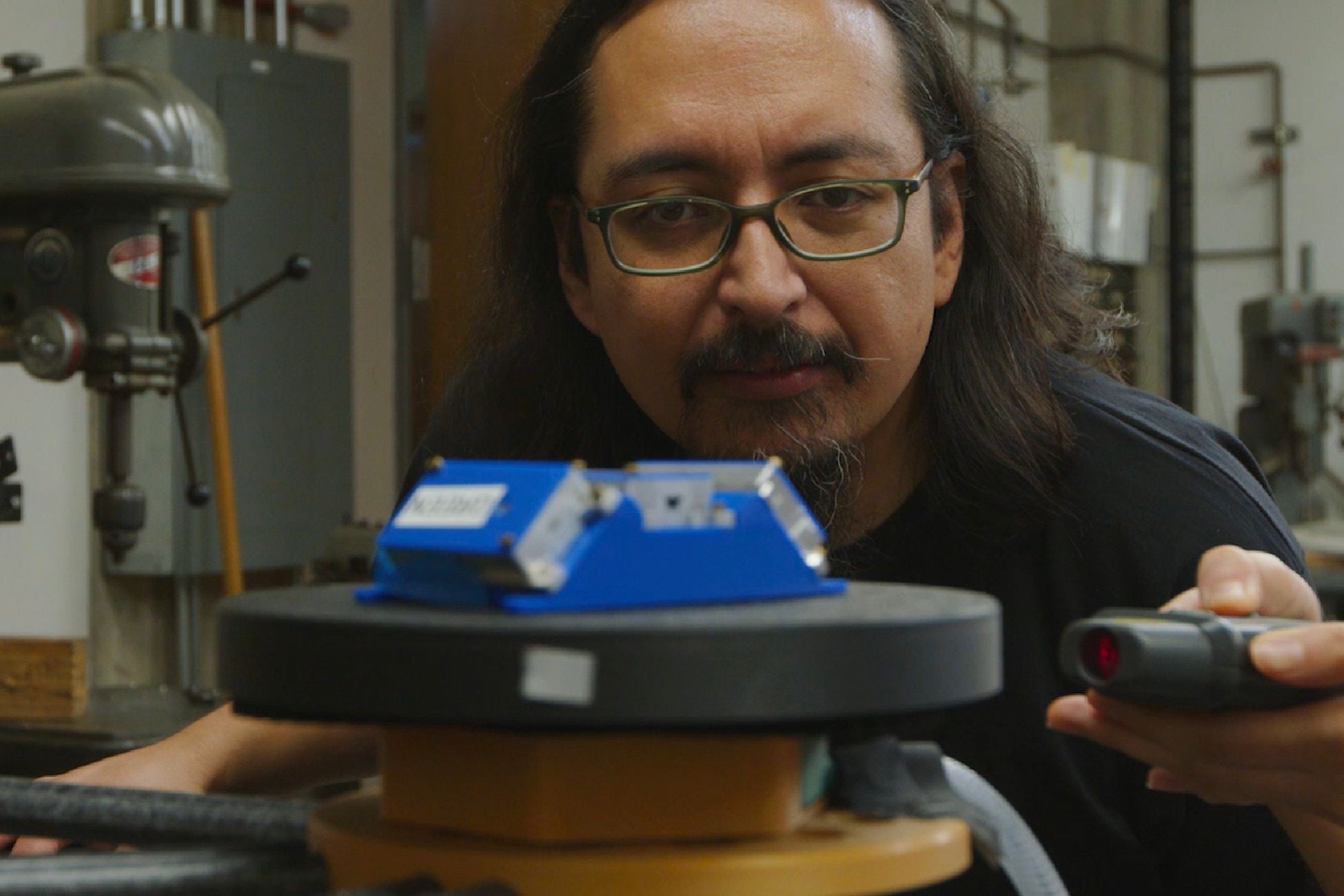 Emmanuel Masongsong '04 uses a remote control to turn a piece of blue and silver equipment he's working on in the materials lab