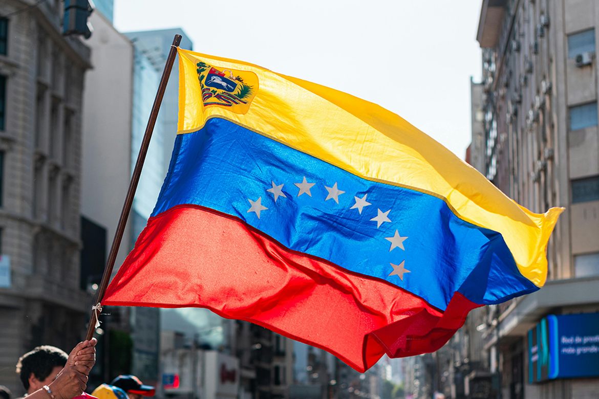 Pair of hands waving a Venezuelan flag in a city street