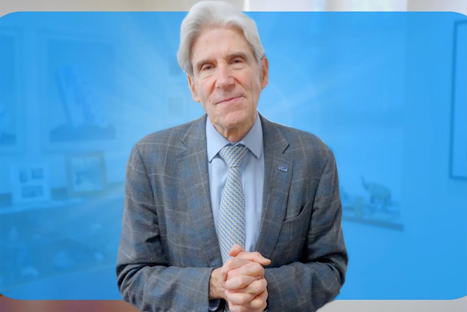 Julio Frenk, in gray suit, light blue button-down and patterned tie, with hands clasped in front