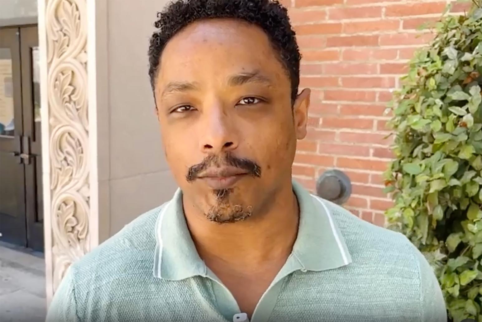 Close-up of person in sage green collared shirt in front of brick building