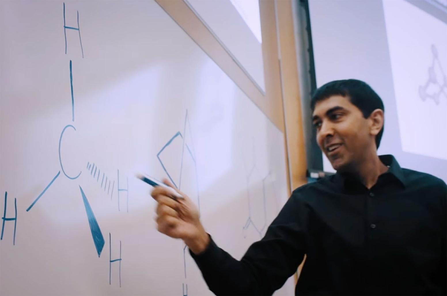 Neil Garg points at a molecule on a whiteboard