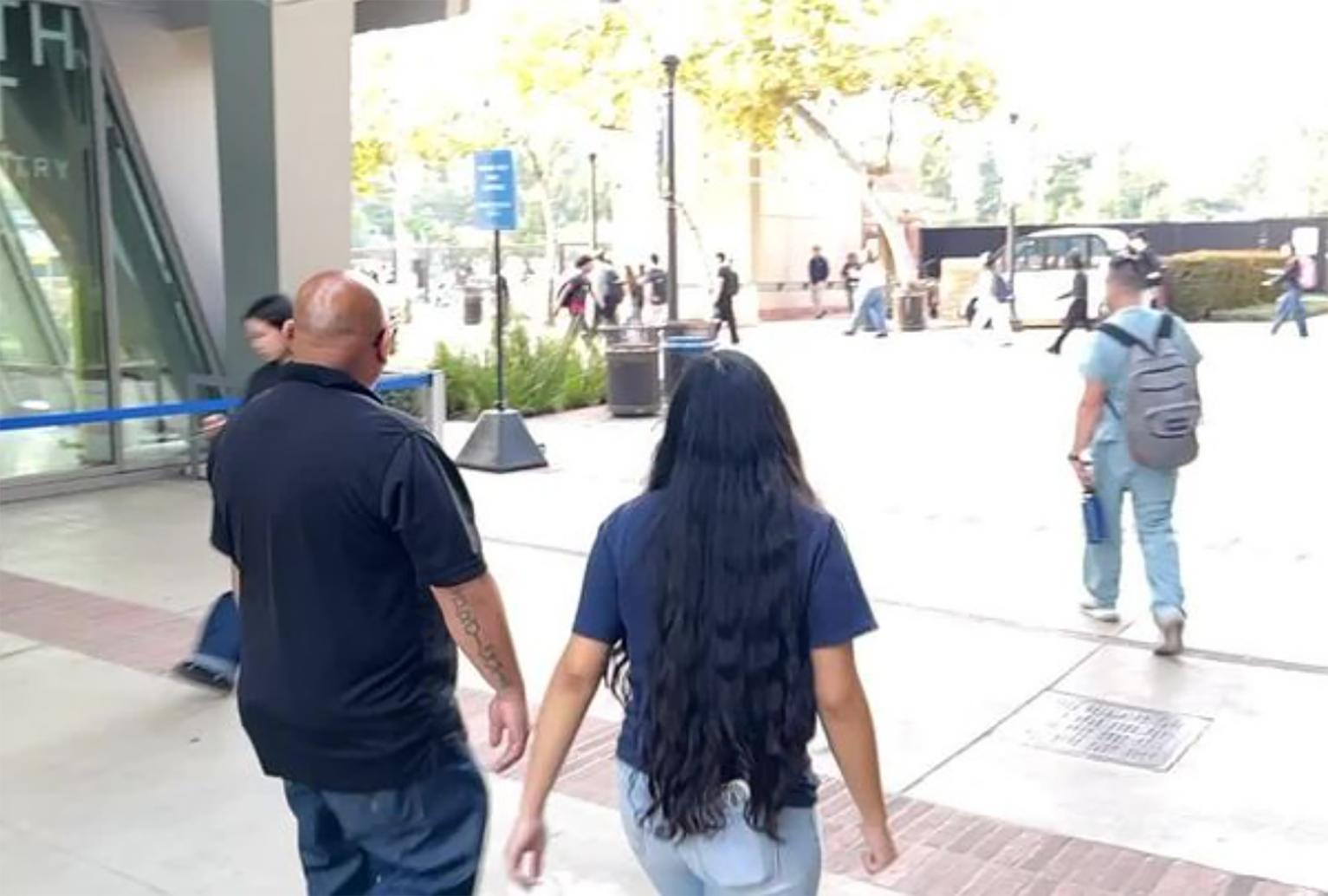 Cesar, left, and Cianna Ulloa pictured from behind walking past a building
