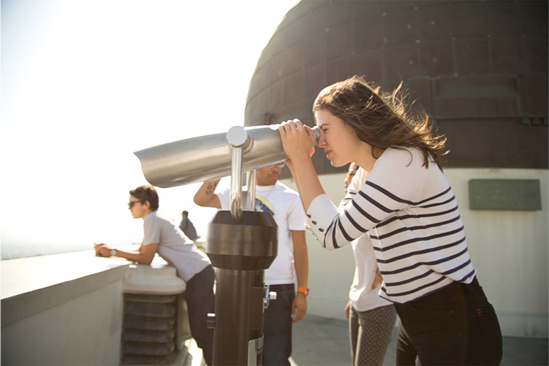 A female student at Griffith Park Observatory peers through a public telescope.
