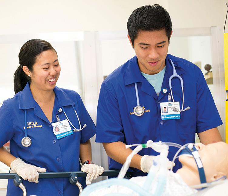 Two nursing students in a hospital setting practice their skills.