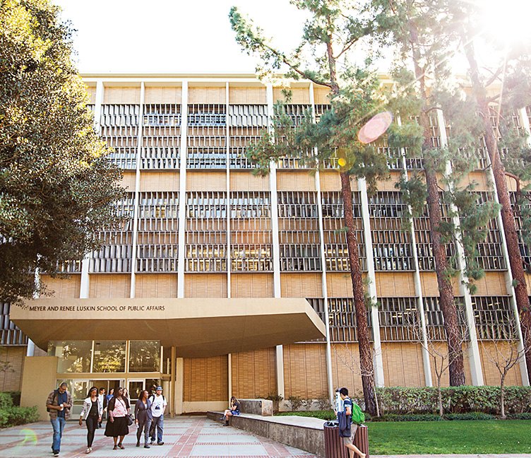 Students walk in a group in front of the Public Affairs building.