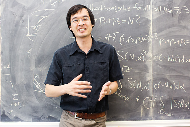 A photo of Terence Tao smiling into the camera in front of a chalkboard