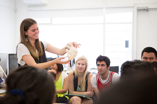 A female student holds up an artistic representation of a human heart for display in class.