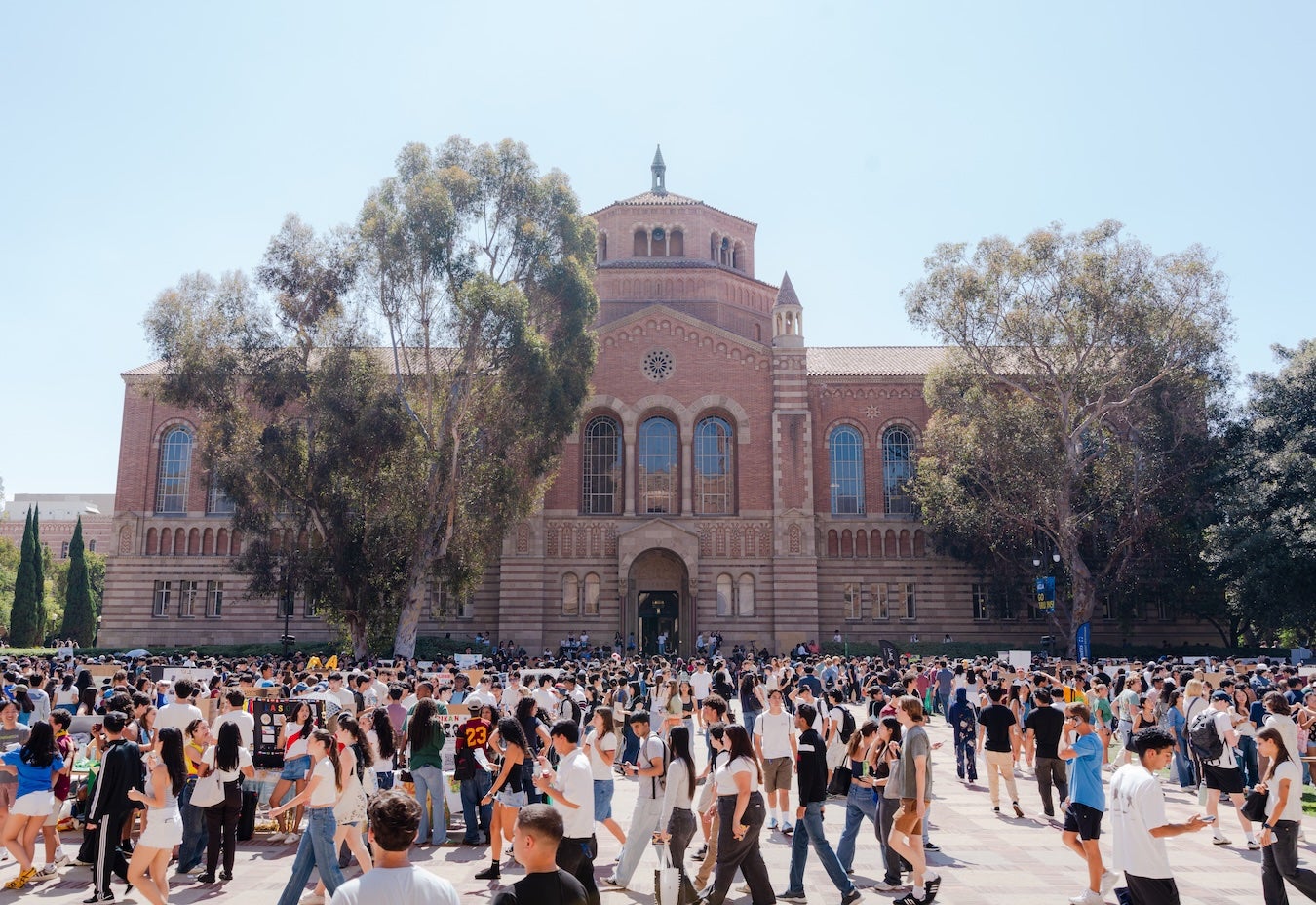 Students walking outdoors at an activities fair with Powell Library in background