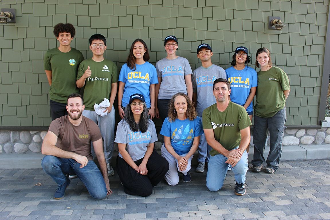 Six people stand in back row, four kneel in front, many wearing green or blue T-shirts